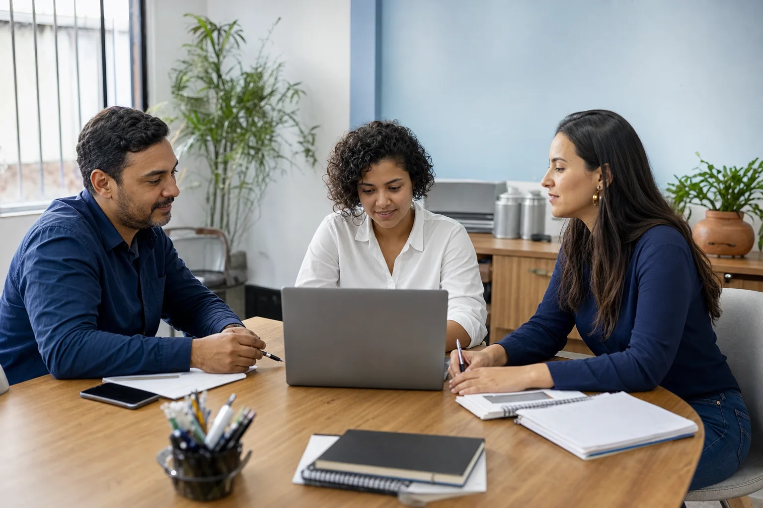 Equipe conversa diante de um computador para organizar a operação digital da empresa.